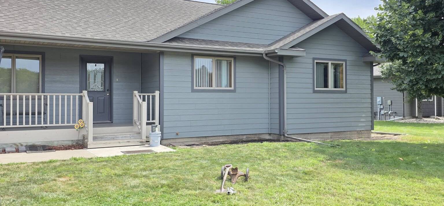 single story house with blue gray siding and a white porch railing