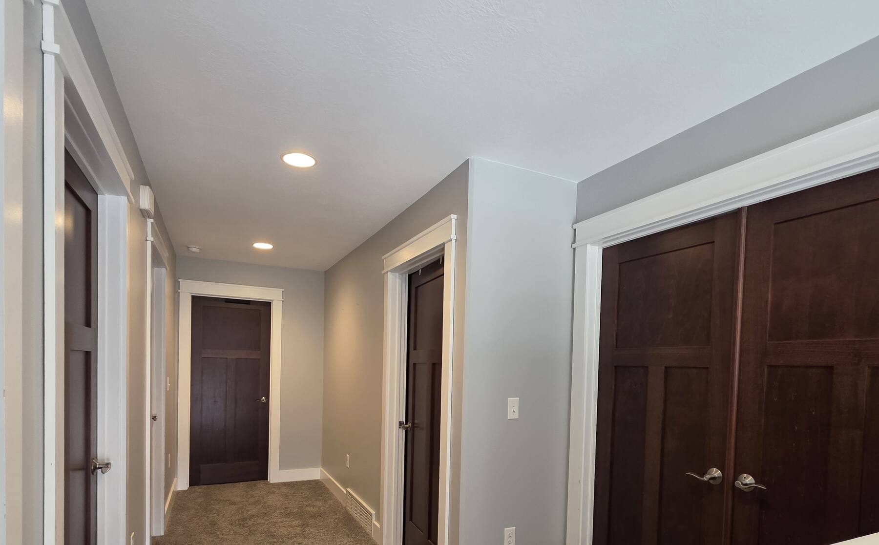 hallway with freshly painted warm gray walls, white trim and dark stained doors