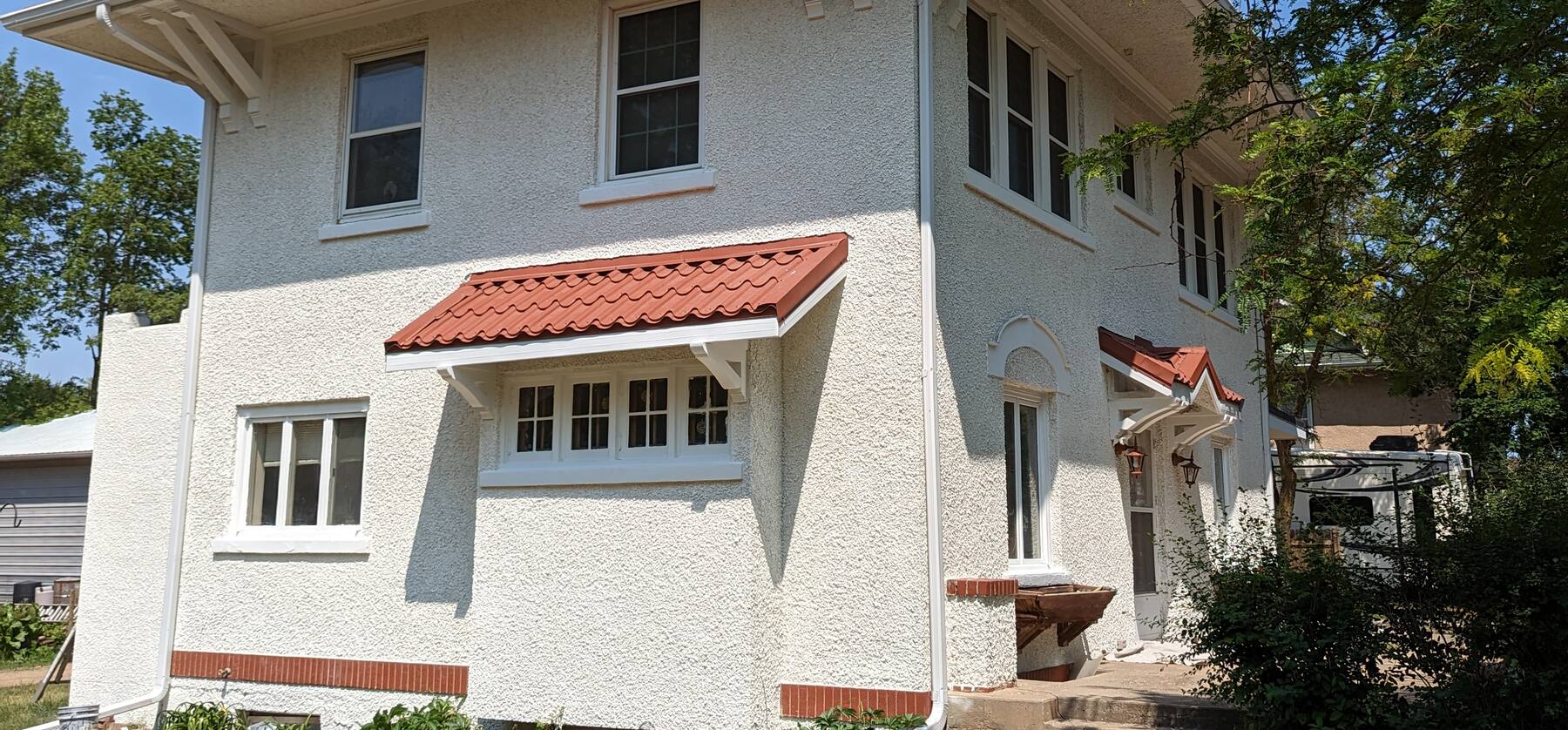 white stucco house with a red tile awning, freshly painted