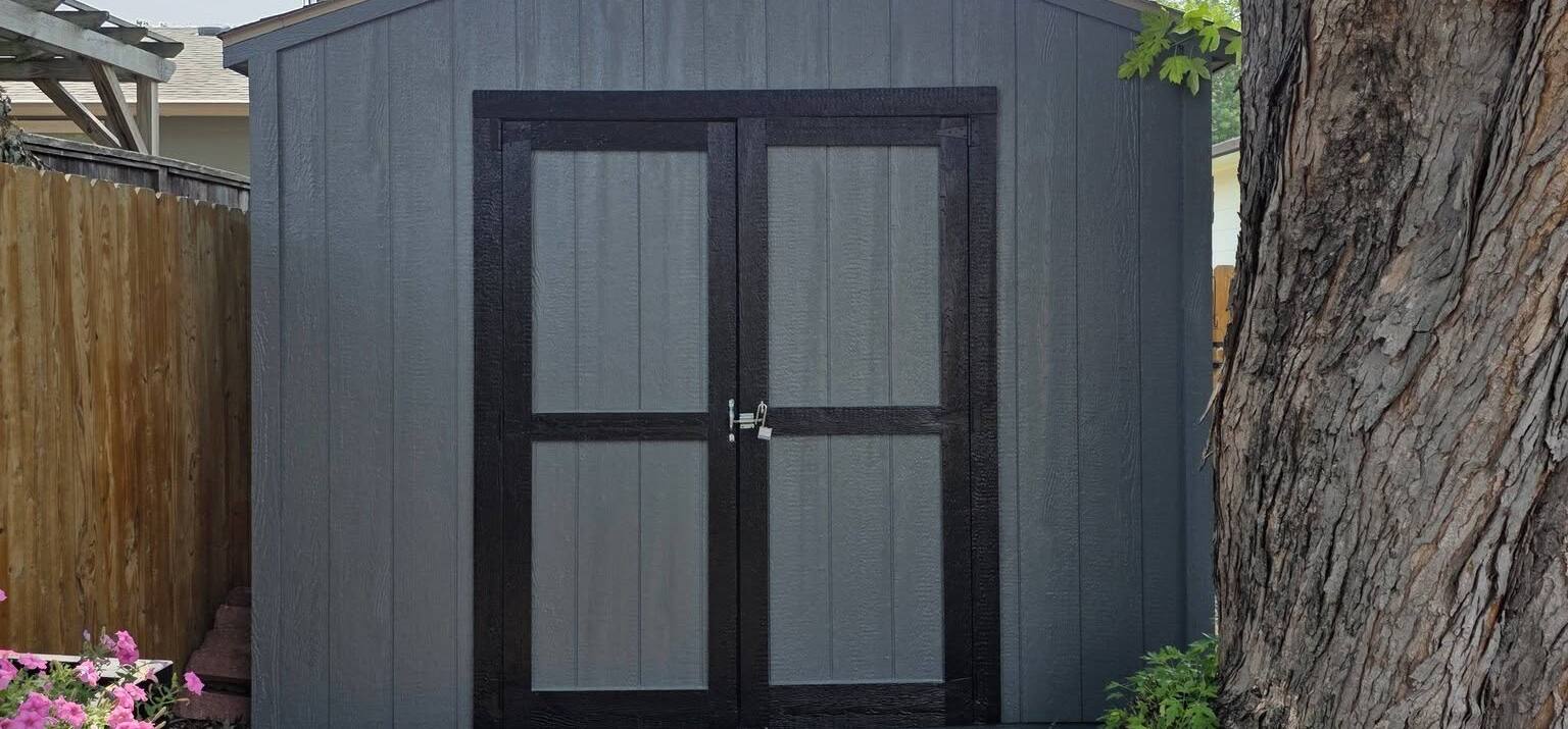 backyard garden shed repainted gray with black trim