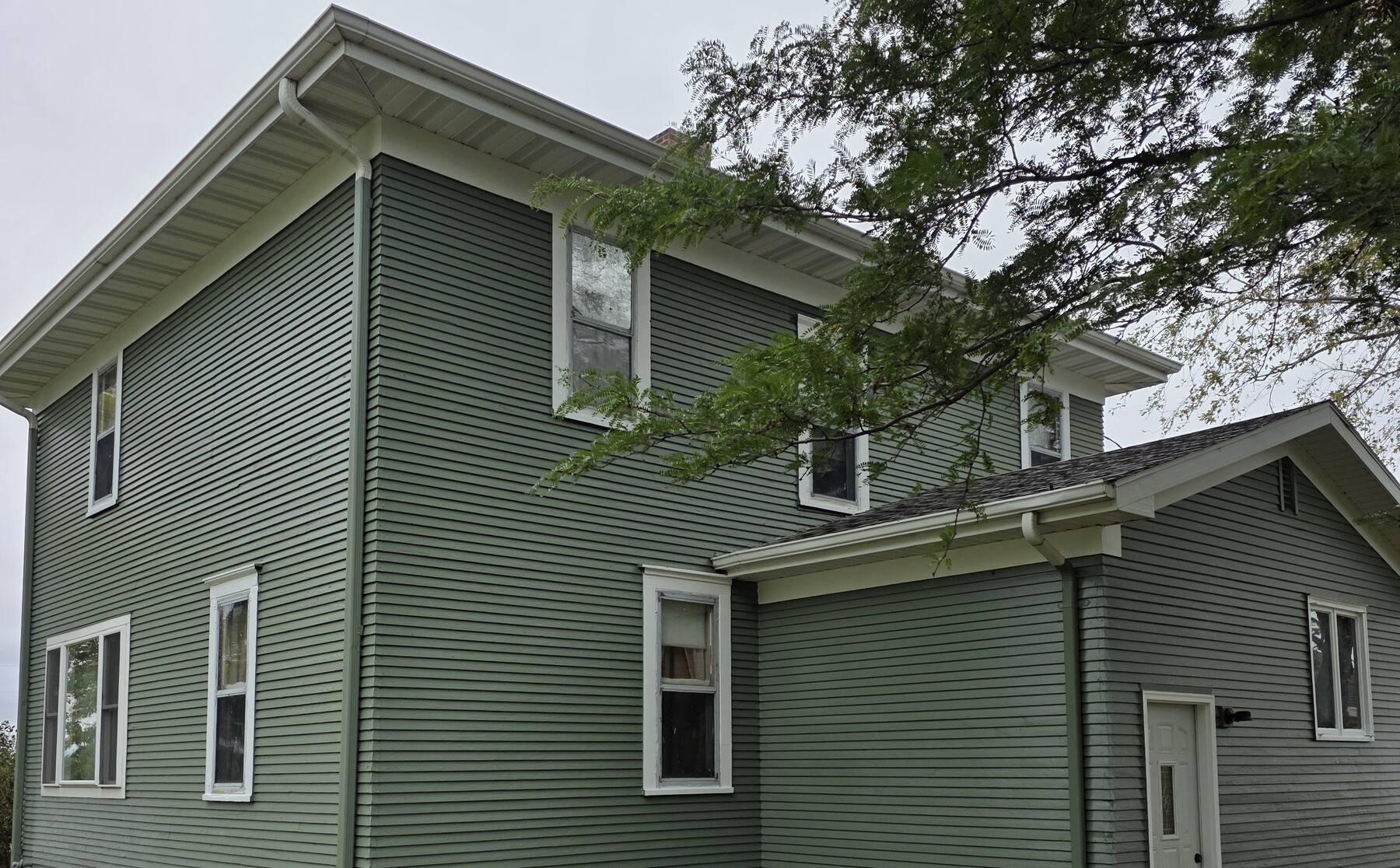 two story farmhouse repainted sage green with white trim