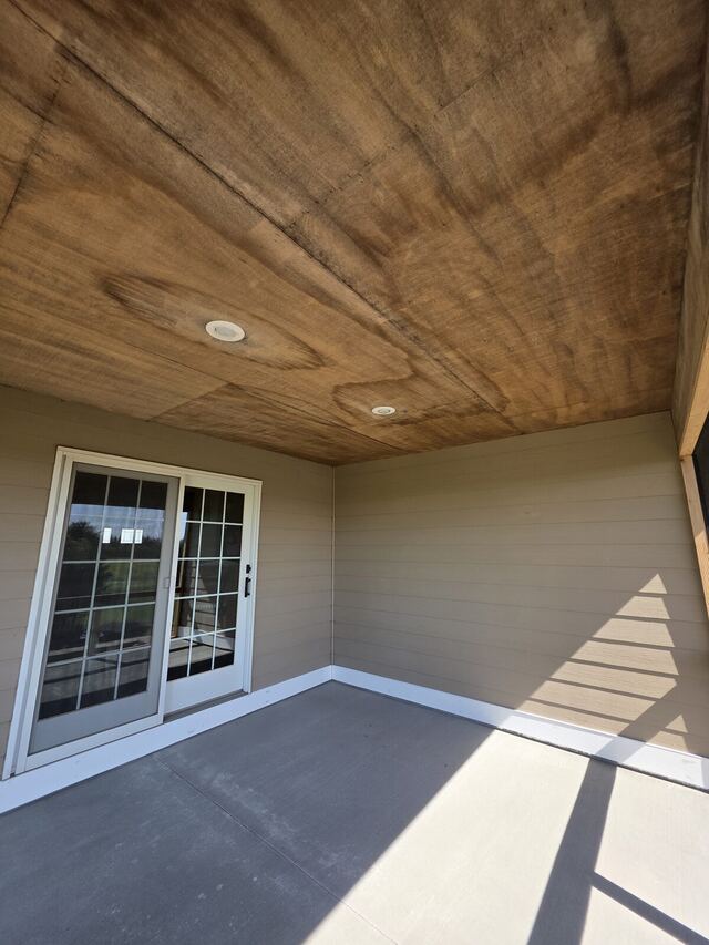 Before: covered patio with a bare wood ceiling painted dark bronze and the siding freshly painted