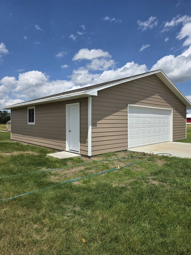 detached garage with freshly painted tan lap siding and white trim
