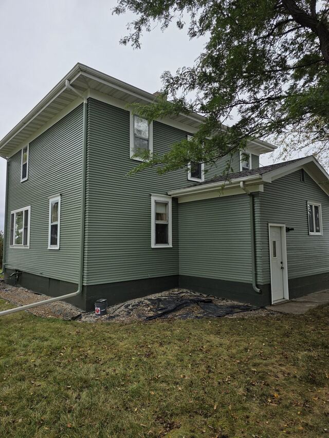 After: two story farmhouse with badly peeling siding, scraped, primed and repainted sage green with white trim