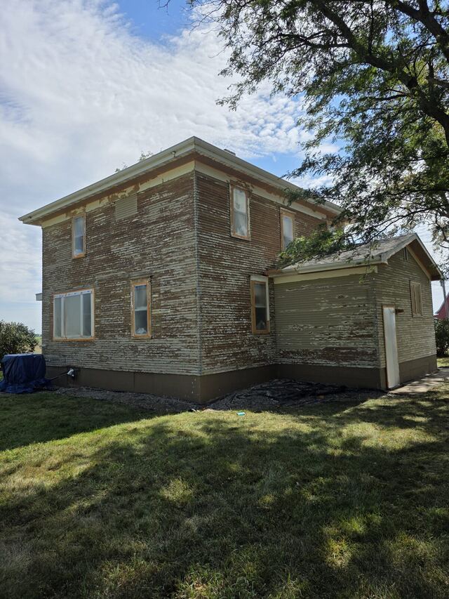 Before: two story farmhouse with badly peeling siding, scraped, primed and repainted sage green with white trim