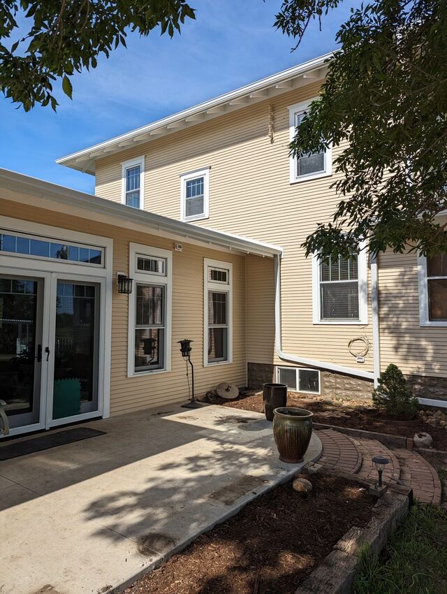 After: older two story home with peeling clapboard and a bare cedar addition, repainted a warm cream with white trim