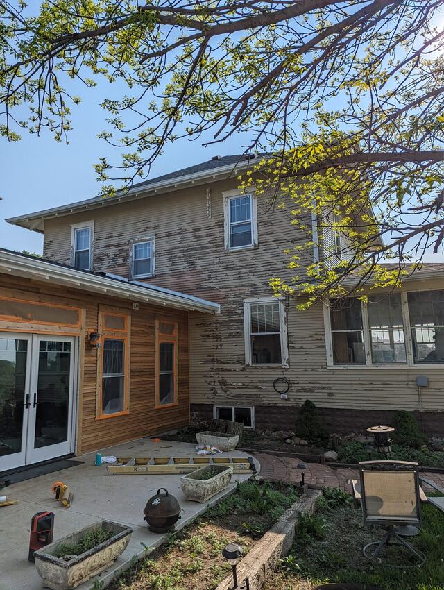 Before: older two story home with peeling clapboard and a bare cedar addition, repainted a warm cream with white trim