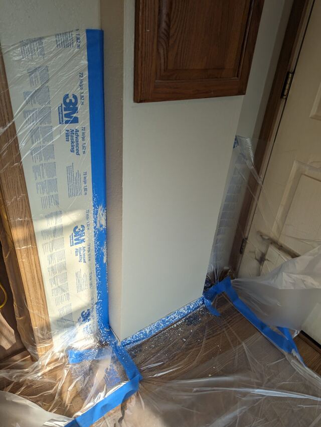 wood floor, door and trim fully wrapped in masking film and tape before painting