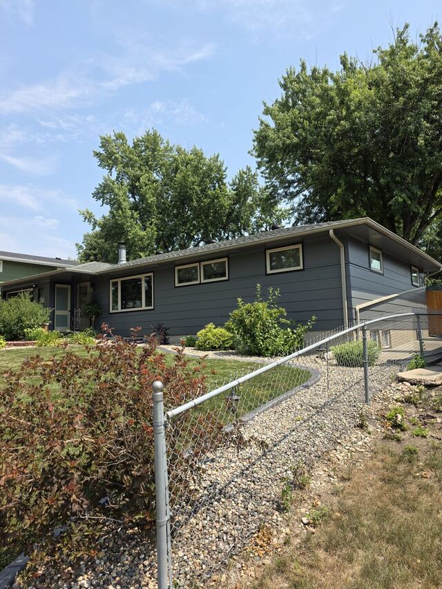 After: mid-century ranch house repainted from pale green to dark slate with black and cream window trim