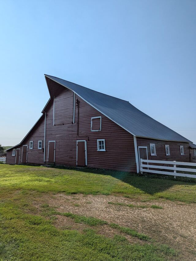 After: large red barn with faded boards repainted barn red with white window and door trim