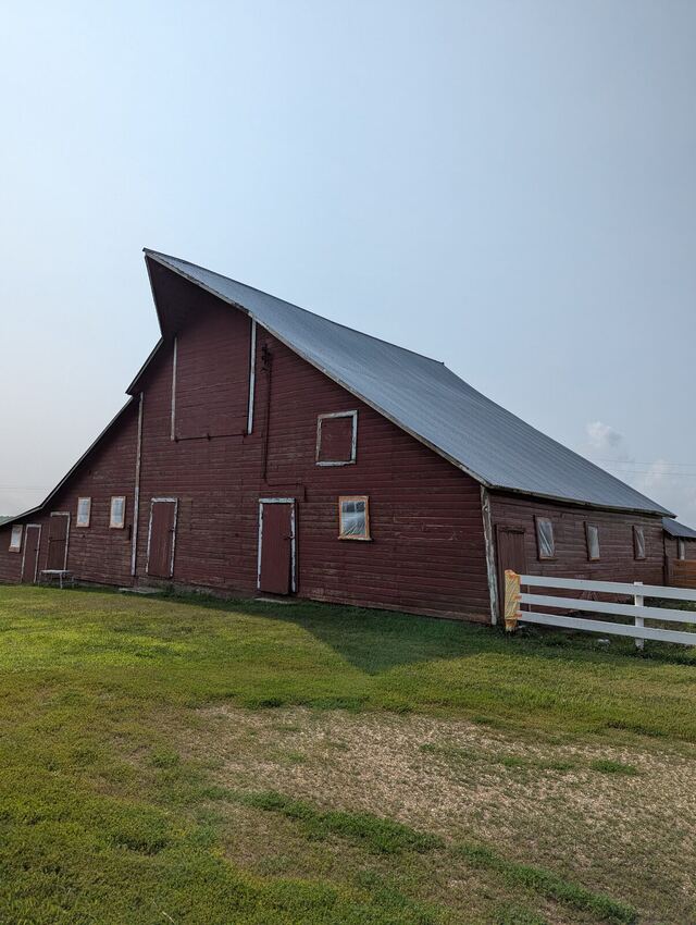 Before: large red barn with faded boards repainted barn red with white window and door trim