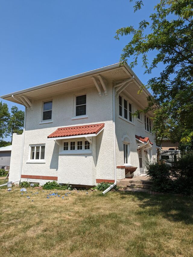 After: two story stucco house with a red tile awning, repainted bright white