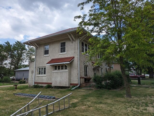 Before: two story stucco house with a red tile awning, repainted bright white
